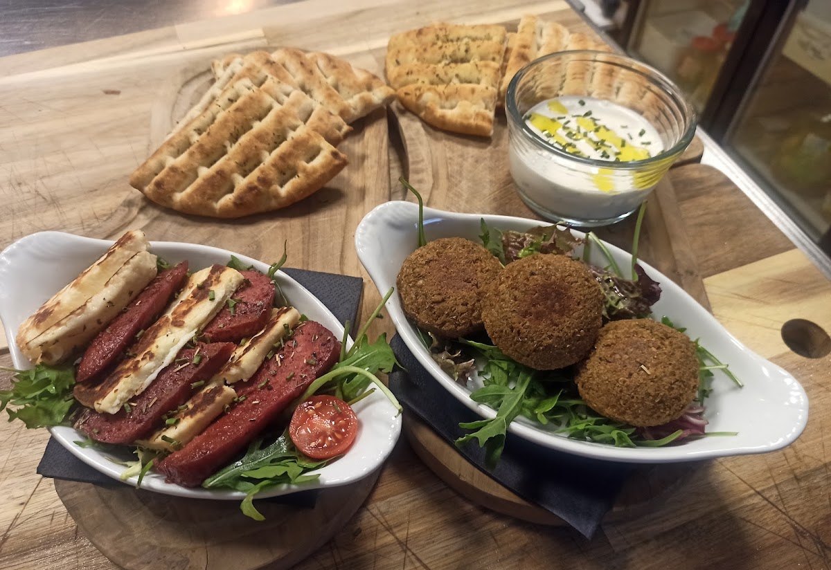 A sharing board: grilled halloumi with spicy sausage, falafel on rocket, warm flatbread and a herbed yoghurt dip.